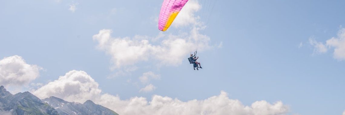 Experience the thrill of paragliding over the stunning Alps on a bright day.